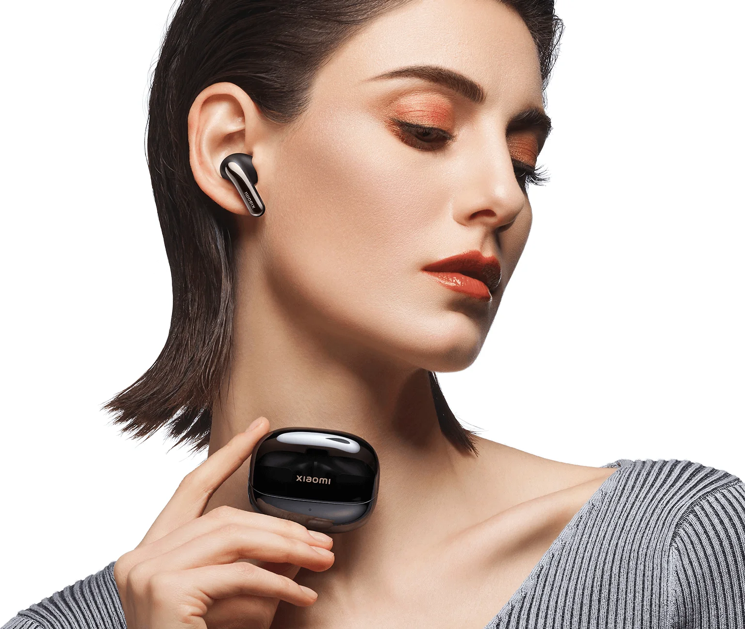 Femme portant des écouteurs noirs, tenant un étui de chargement. Logo Xiaomi.