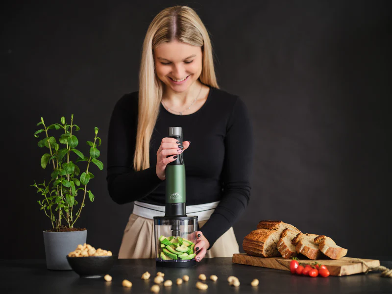 Nő kézi mixerrel avokádót és kenyeret készít.