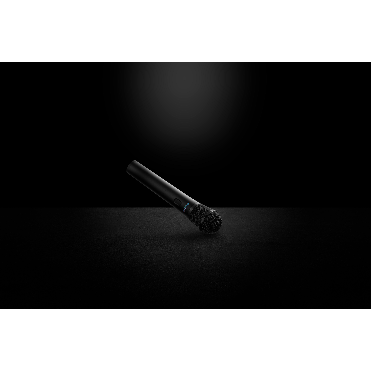 A black microphone on a dark surface, angled slightly, with a black background.