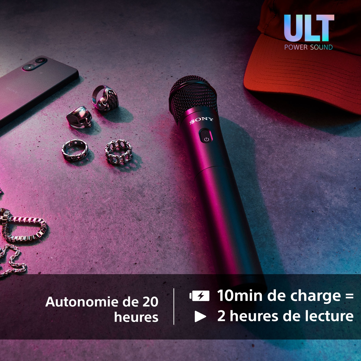 Un microphone noir avec le logo Sony, des bagues, un téléphone et un chapeau sur une surface en béton.