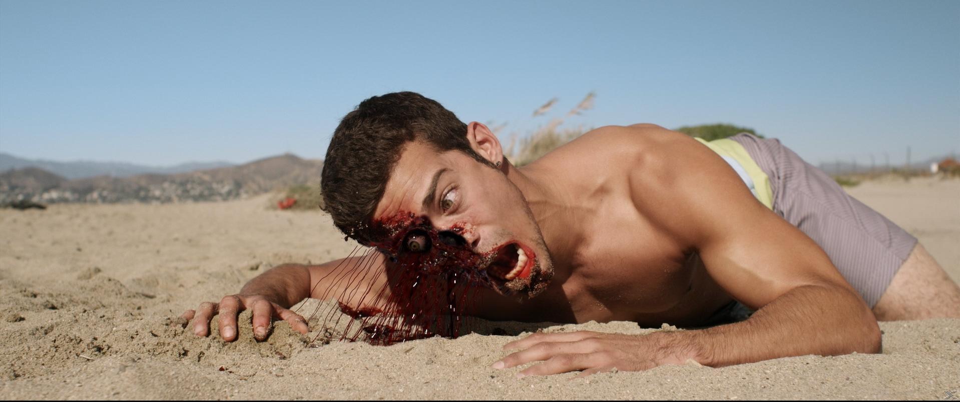 Mann am Strand mit Augenverletzung. Blut und Wunddetail sichtbar.