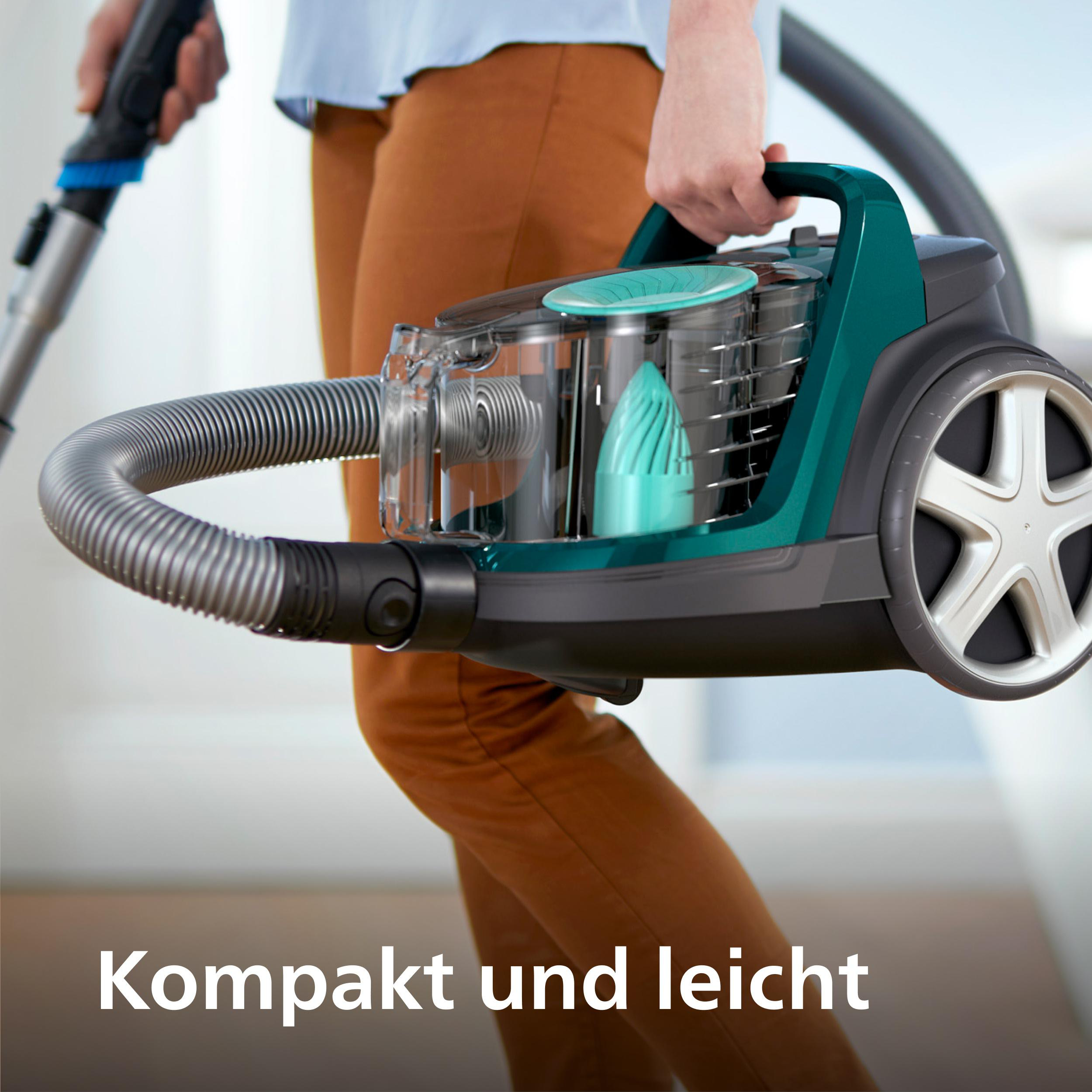 Eine Person hält einen grün-schwarzen Staubsauger und hebt das kompakte Design hervor.
