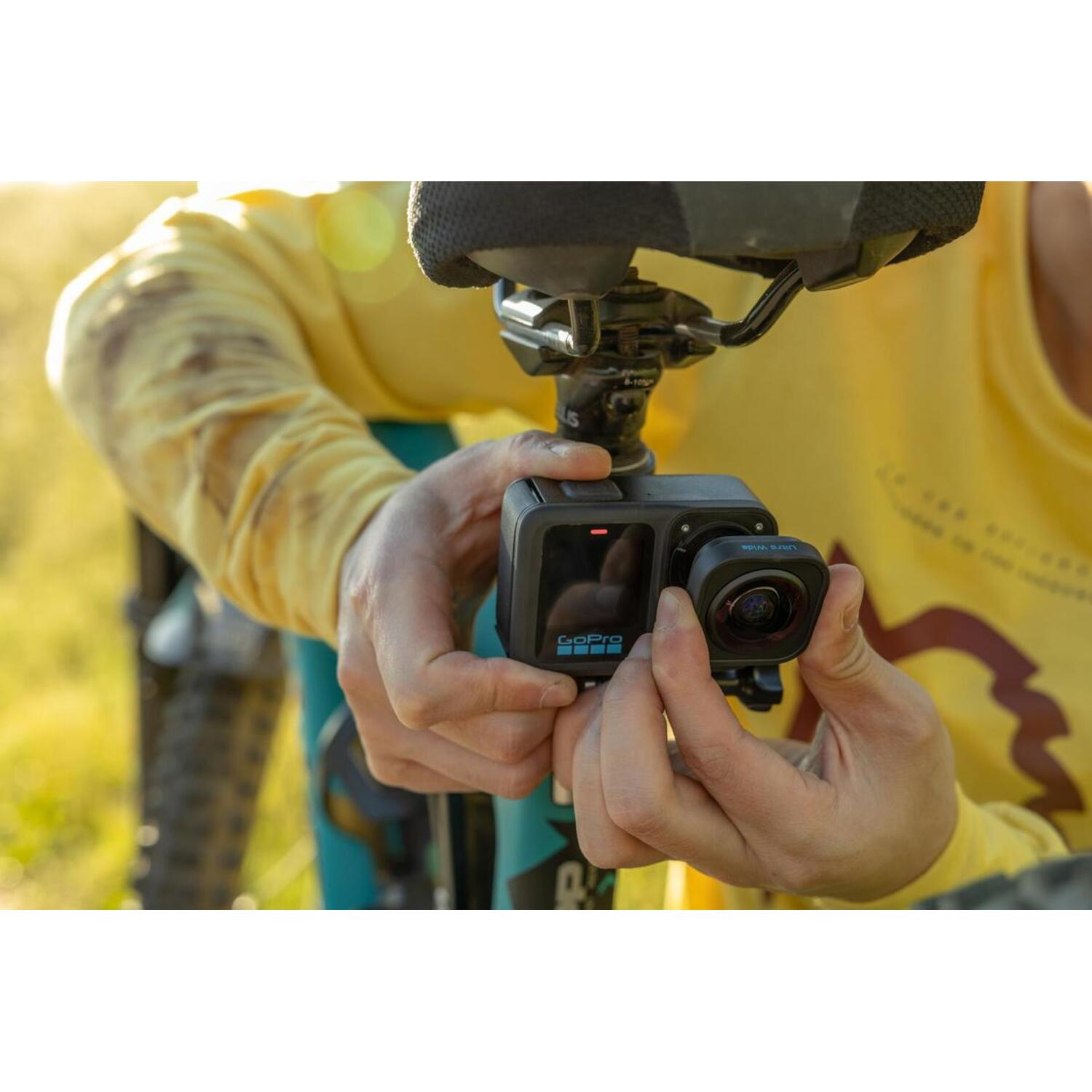 De handen van een persoon die een GoPro-camera aanpast die aan een zadelpen van een fiets is bevestigd.