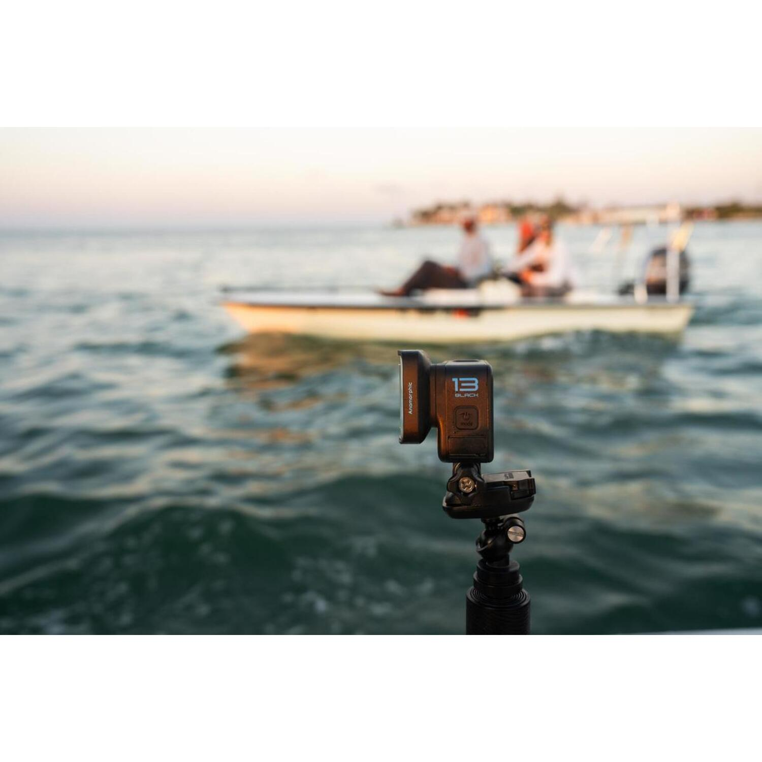 Een camera is op een statief gemonteerd, met een boot op de achtergrond op het water.