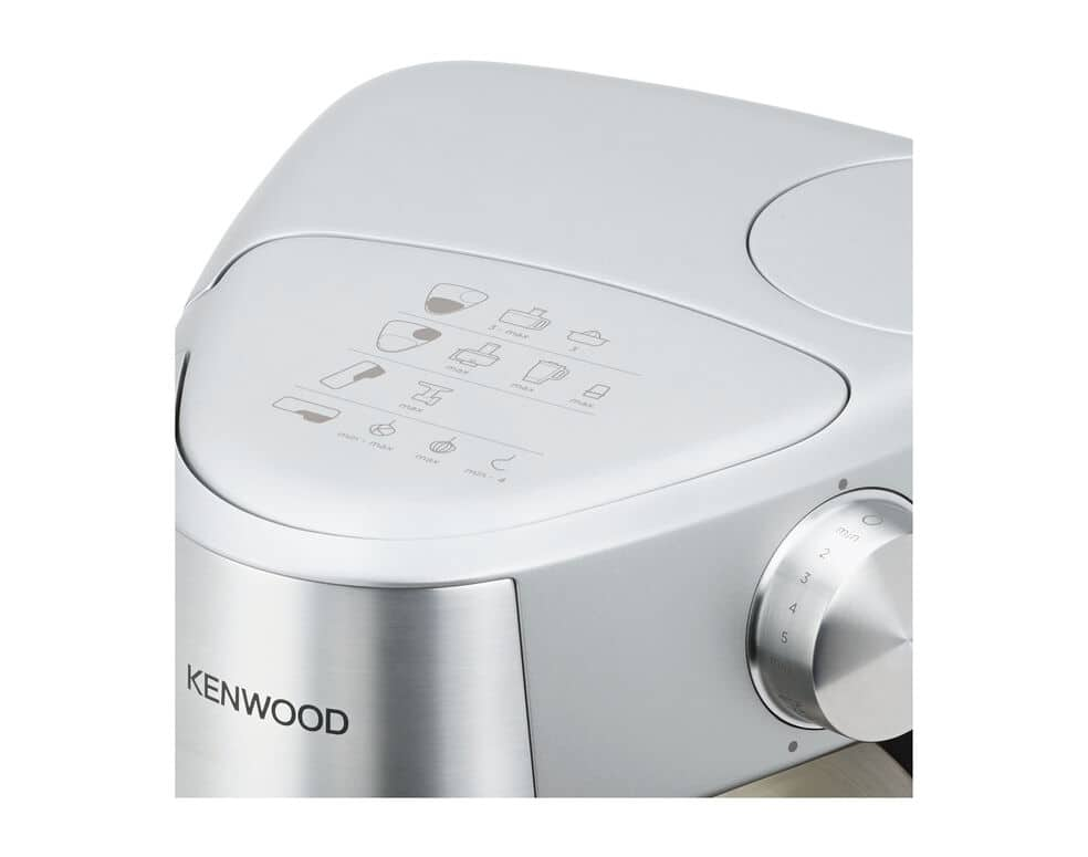 Egy ezüst Kenwood konyhai készülék közeli képe, vezérlőtárcsákkal és funkcióikonokkal a tetején.