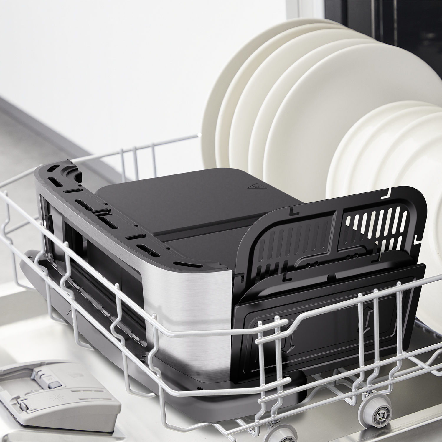 Dishwasher basket with a black insert, and white plates in the background.