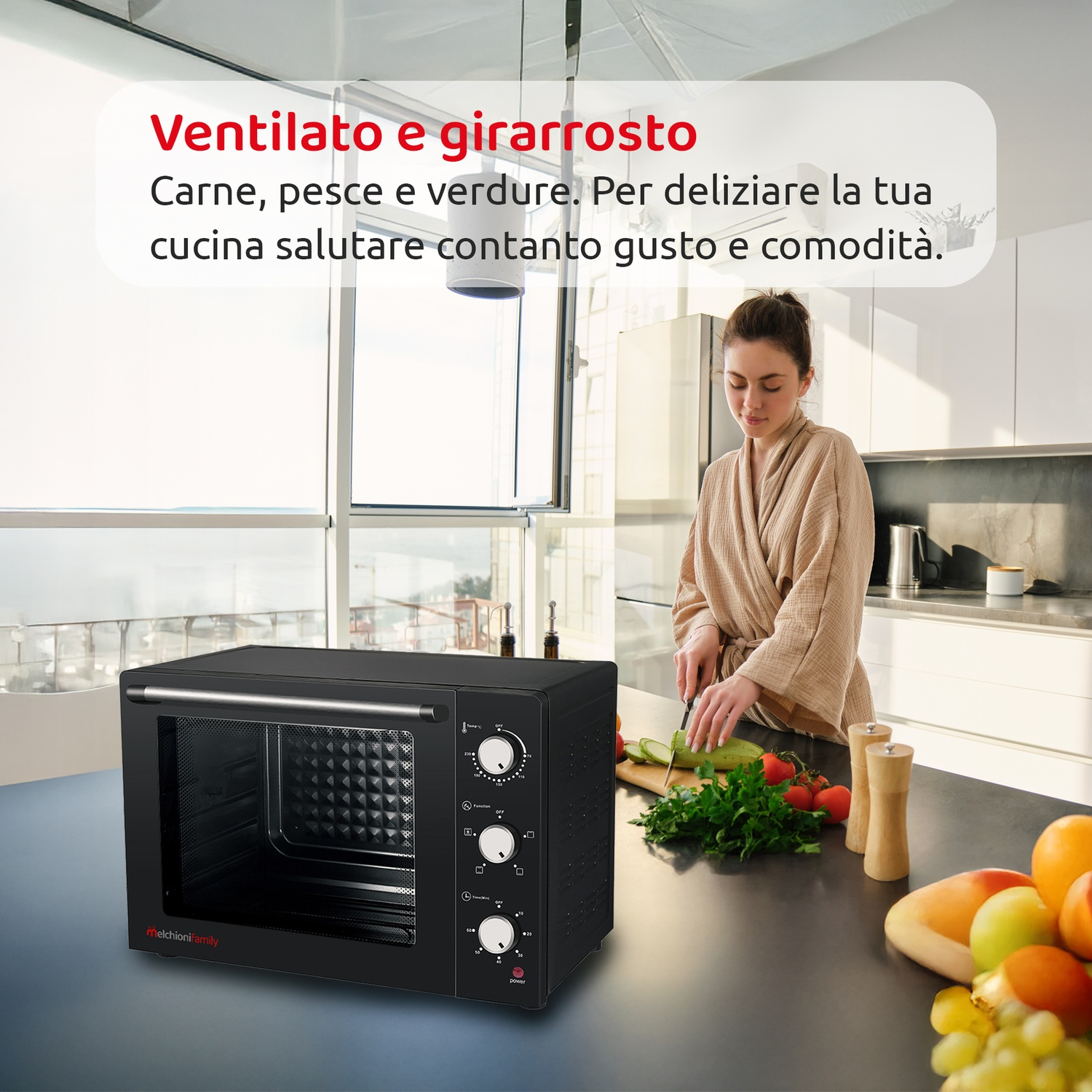 Forno nero su un bancone, una donna taglia verdure sullo sfondo.