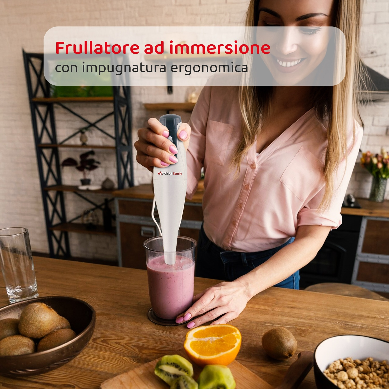 Donna usa un frullatore a immersione in cucina, frullando un frullato rosa.