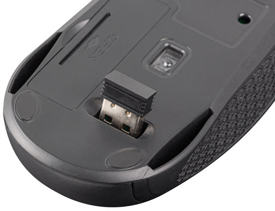 Egy fekete számítógépes egér alja, USB vevővel.