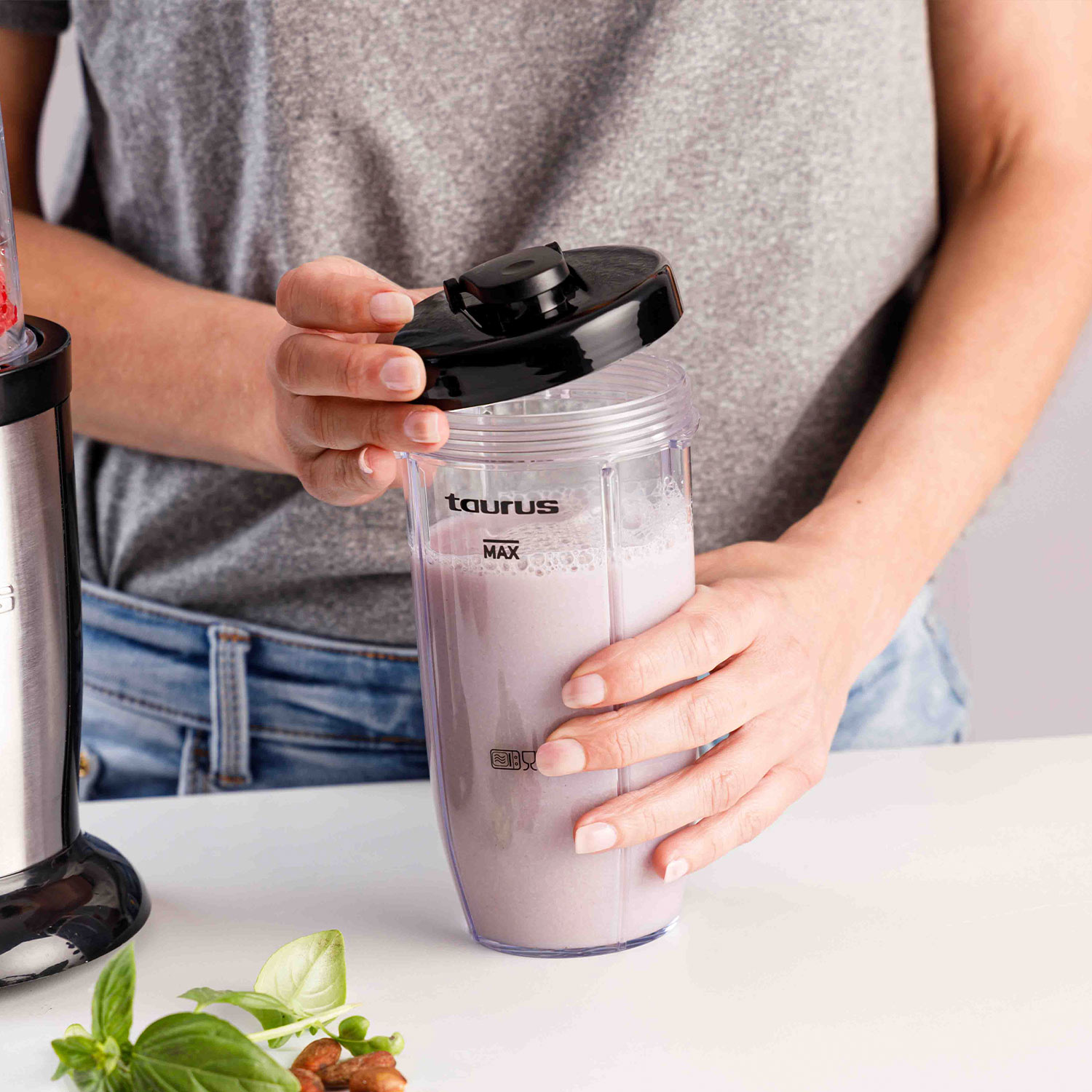 Una persona abriendo una taza de licuadora llena de líquido morado.