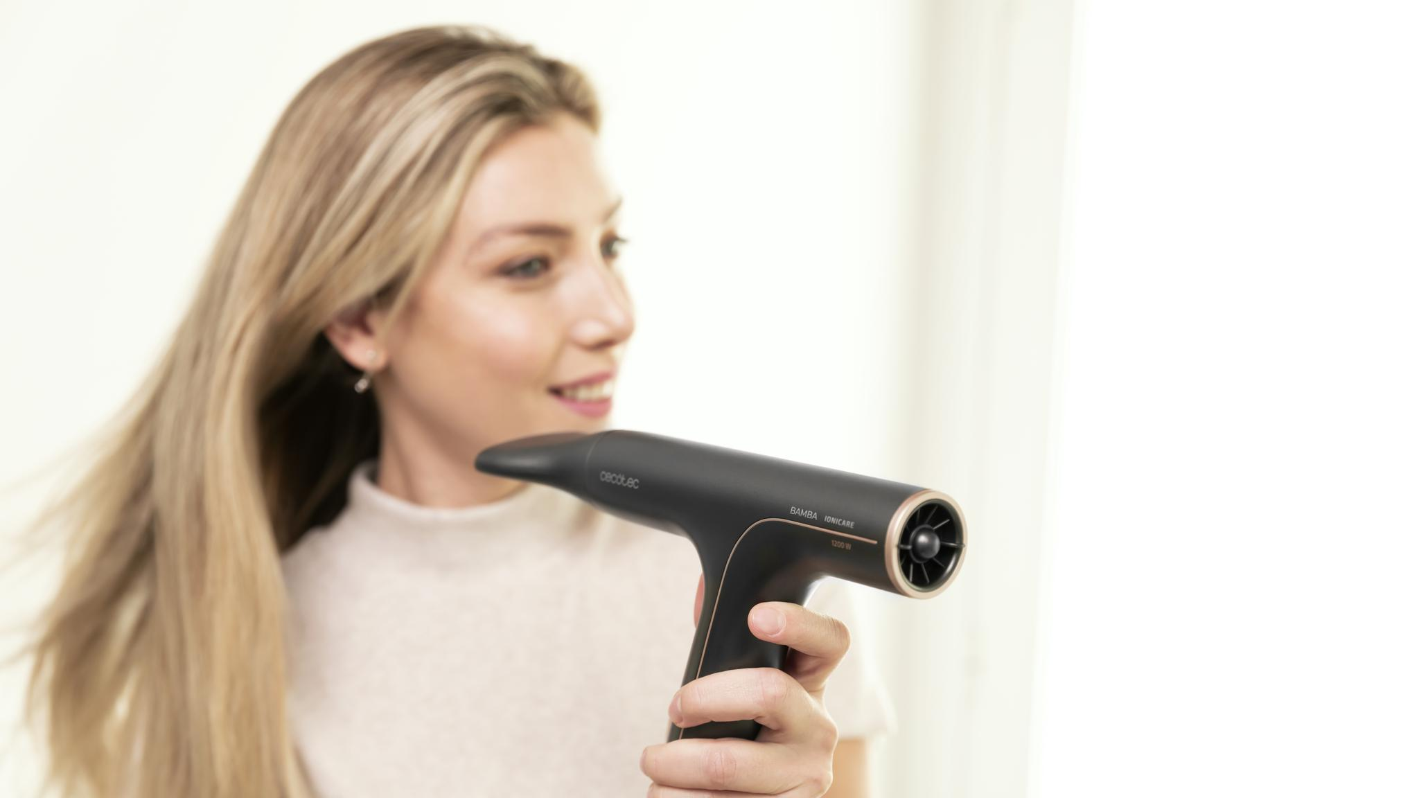 Kobieta z blond włosami używa czarnej suszarki do włosów.