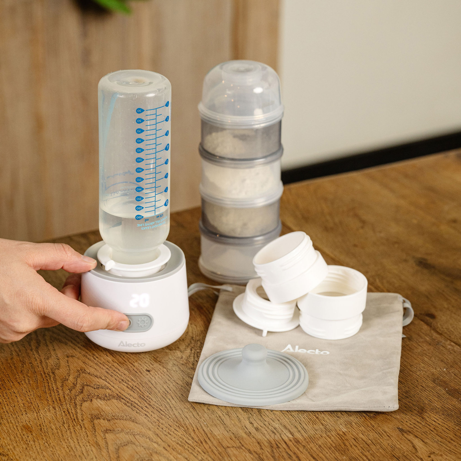 A baby bottle warmer with a bottle and a container of formula. There are other supplies.