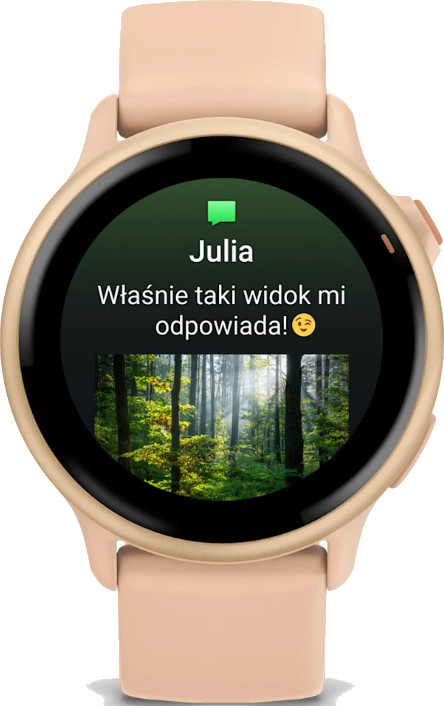 Zegarek smartwatch w kolorze brzoskwiniowym wyświetla wiadomość od „Julii” ze zdjęciem lasu i emotikonem uśmiechniętej twarzy.