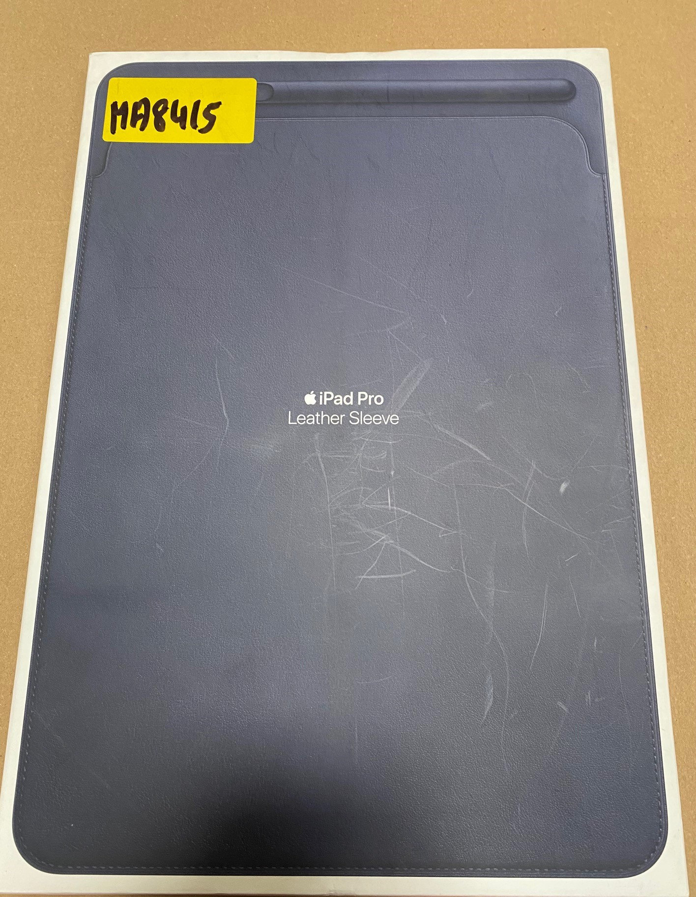 Skórzane etui na iPad Pro w pudełku z żółtą etykietą z napisem 'MA8415'.