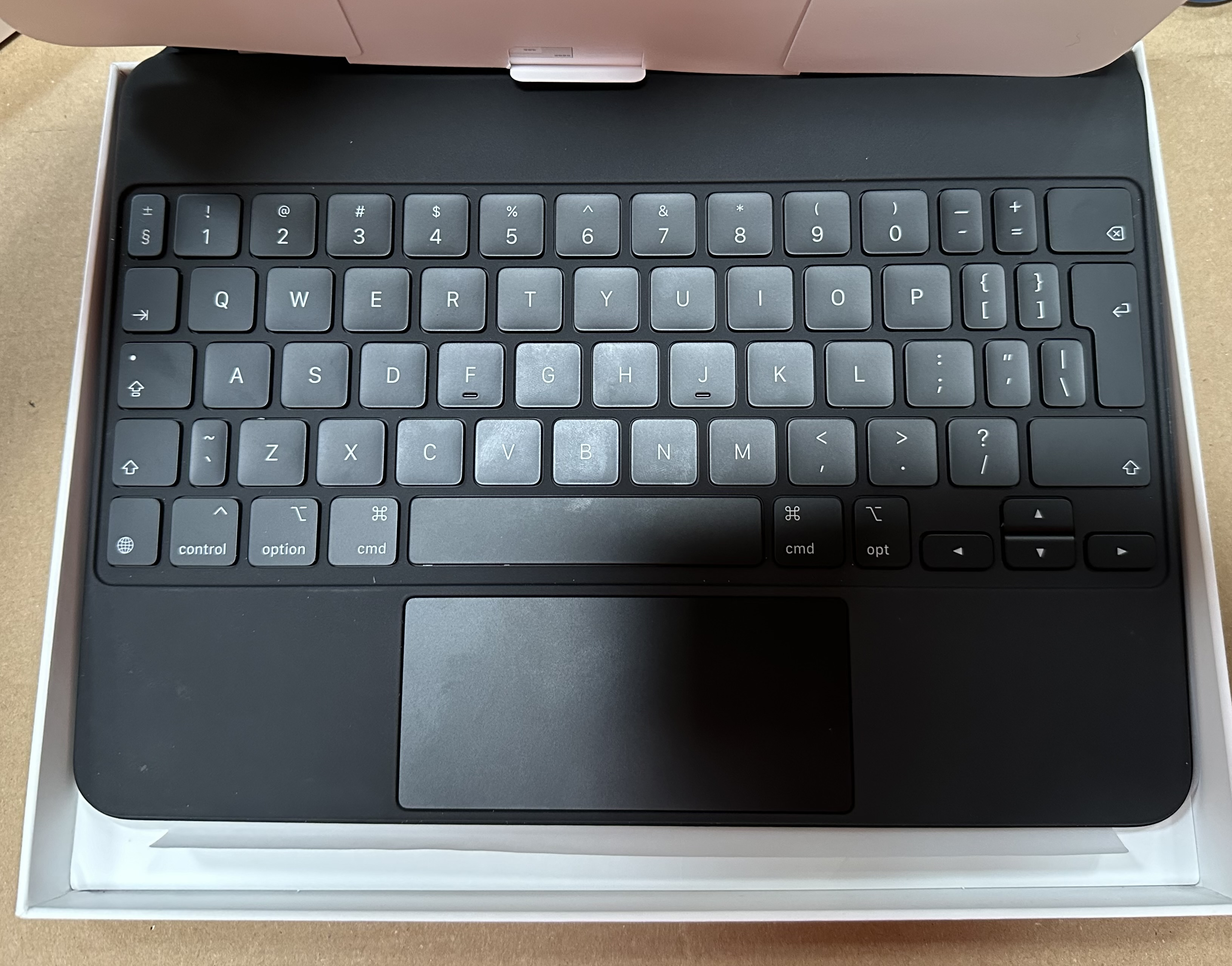 Czarna klawiatura z touchpadem w białym pudełku.