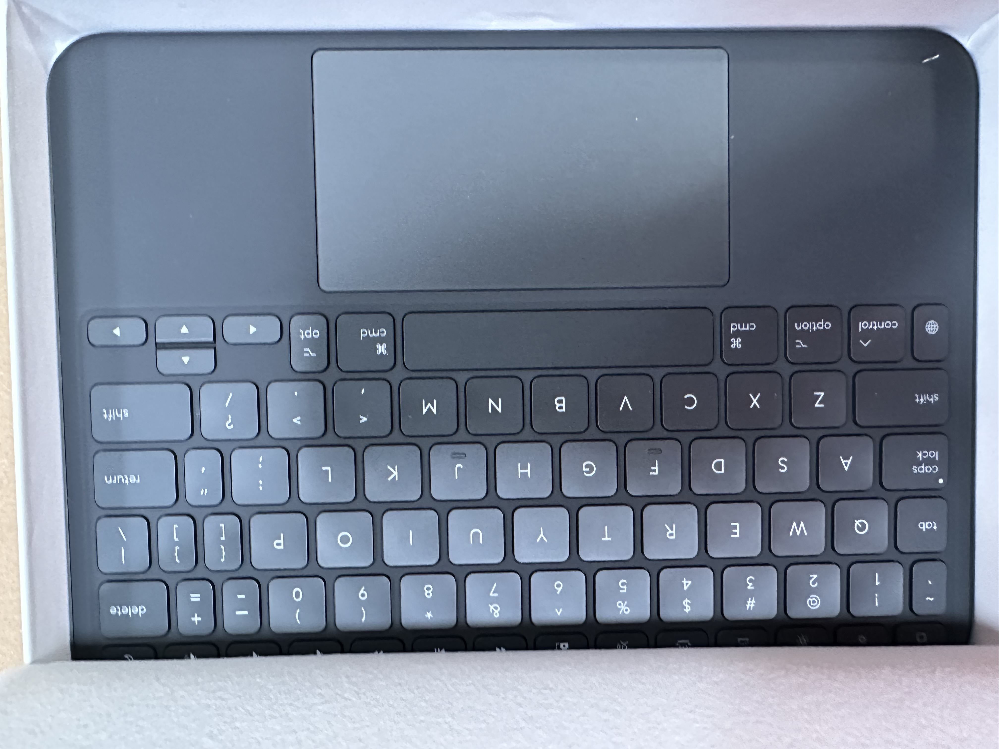 Widok z góry na czarną klawiaturę z panelem dotykowym w białym pudełku.