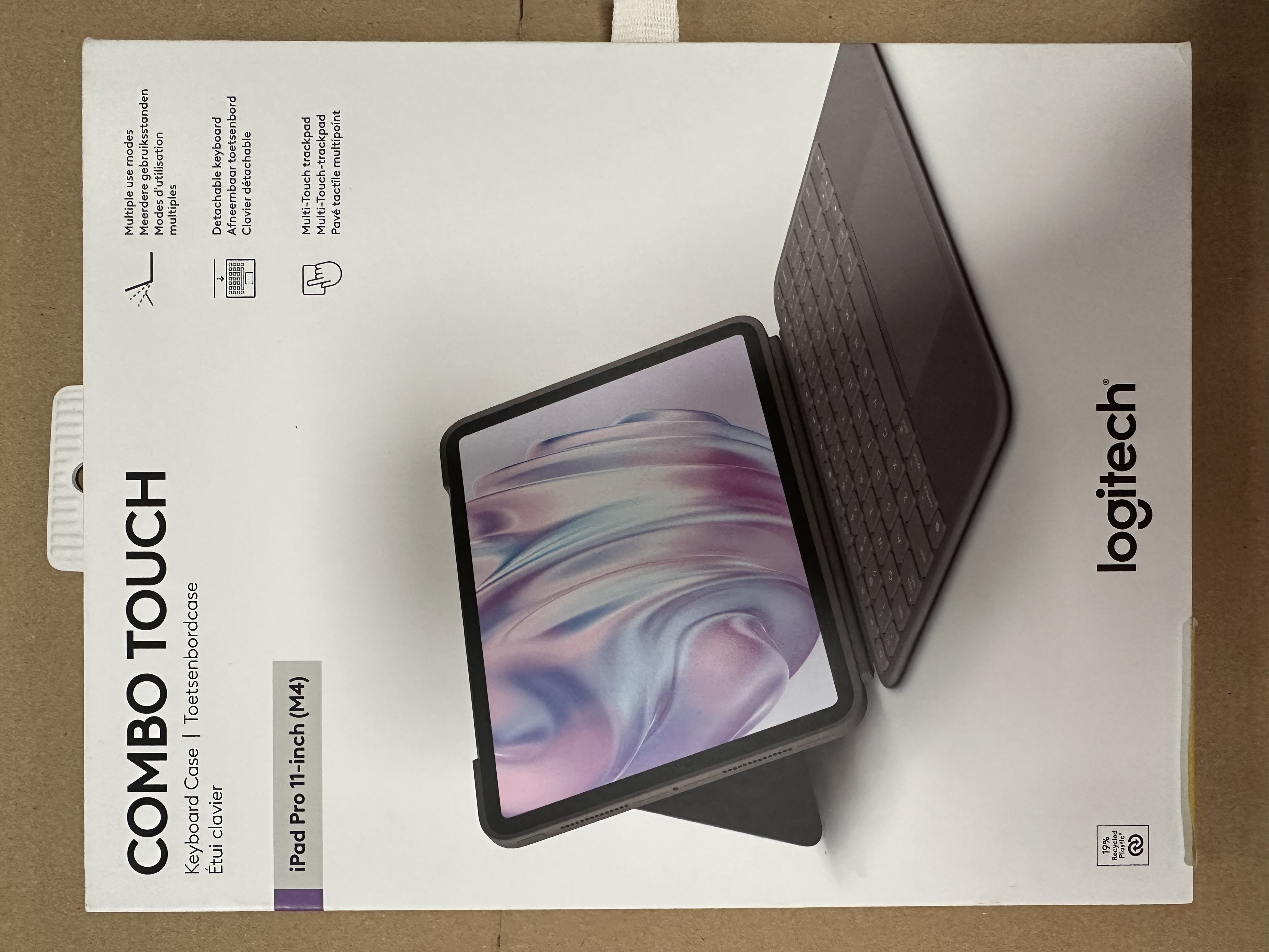 Białe pudełko z tabletem i etui na klawiaturę. Marka to Logitech.