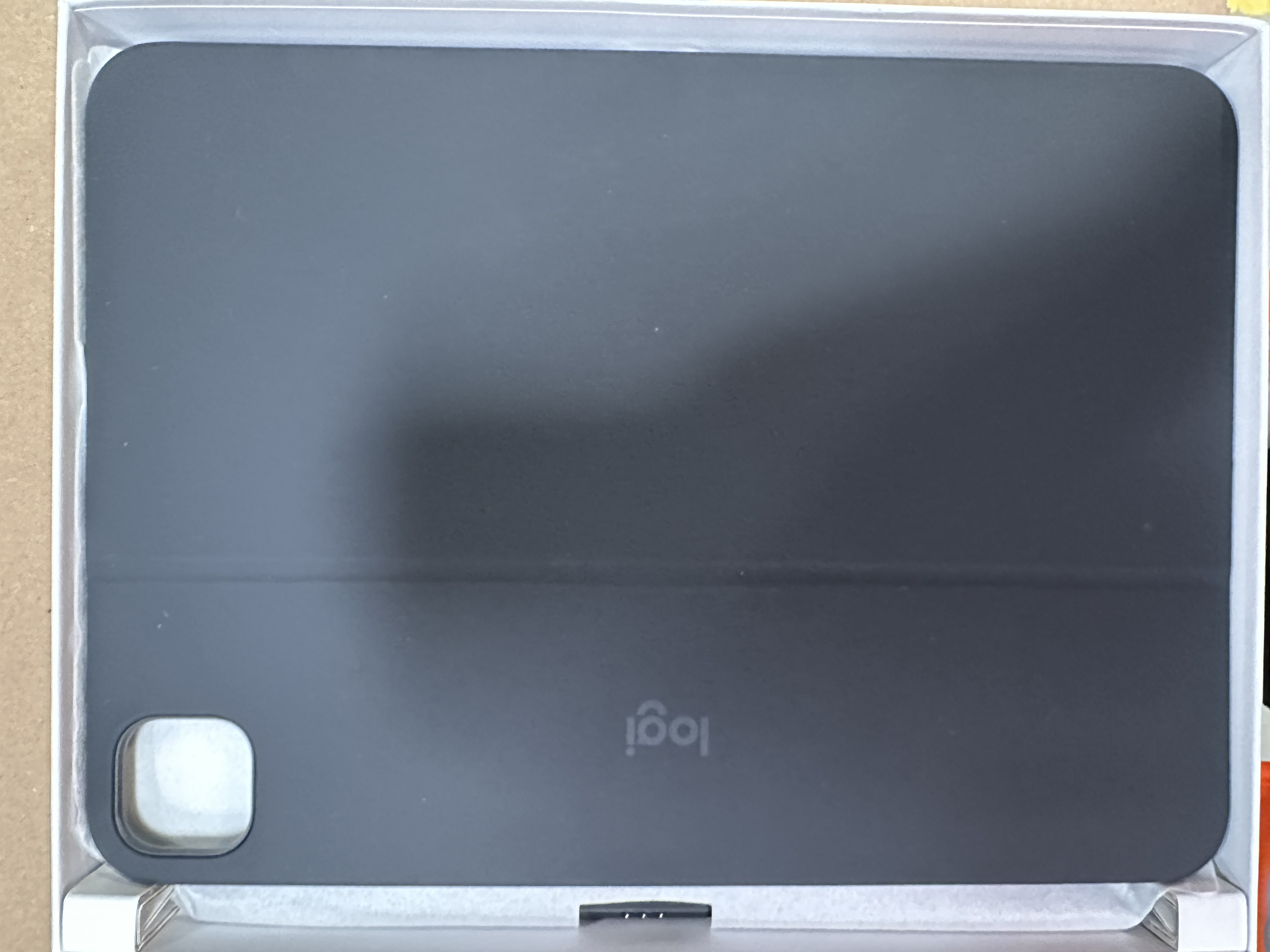 Szara osłona klawiatury Logi w opakowaniu. Osłona jest zamknięta, widoczne logo Logi.