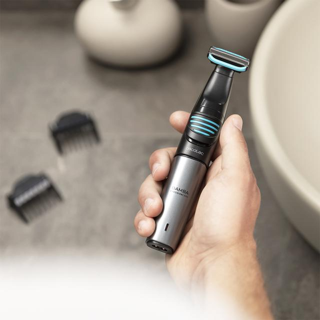 Dłoń osoby trzymająca srebrno-czarną golarkę elektryczną z dwoma nakładkami do przycinania.