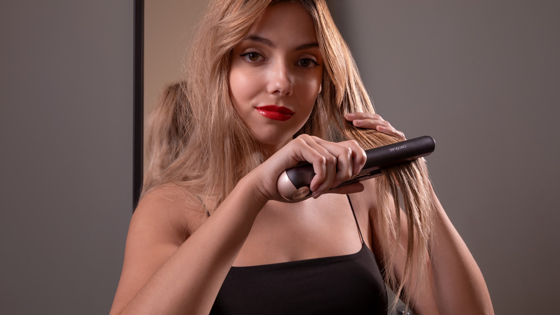 Kobieta z czerwoną szminką używa prostownicy.