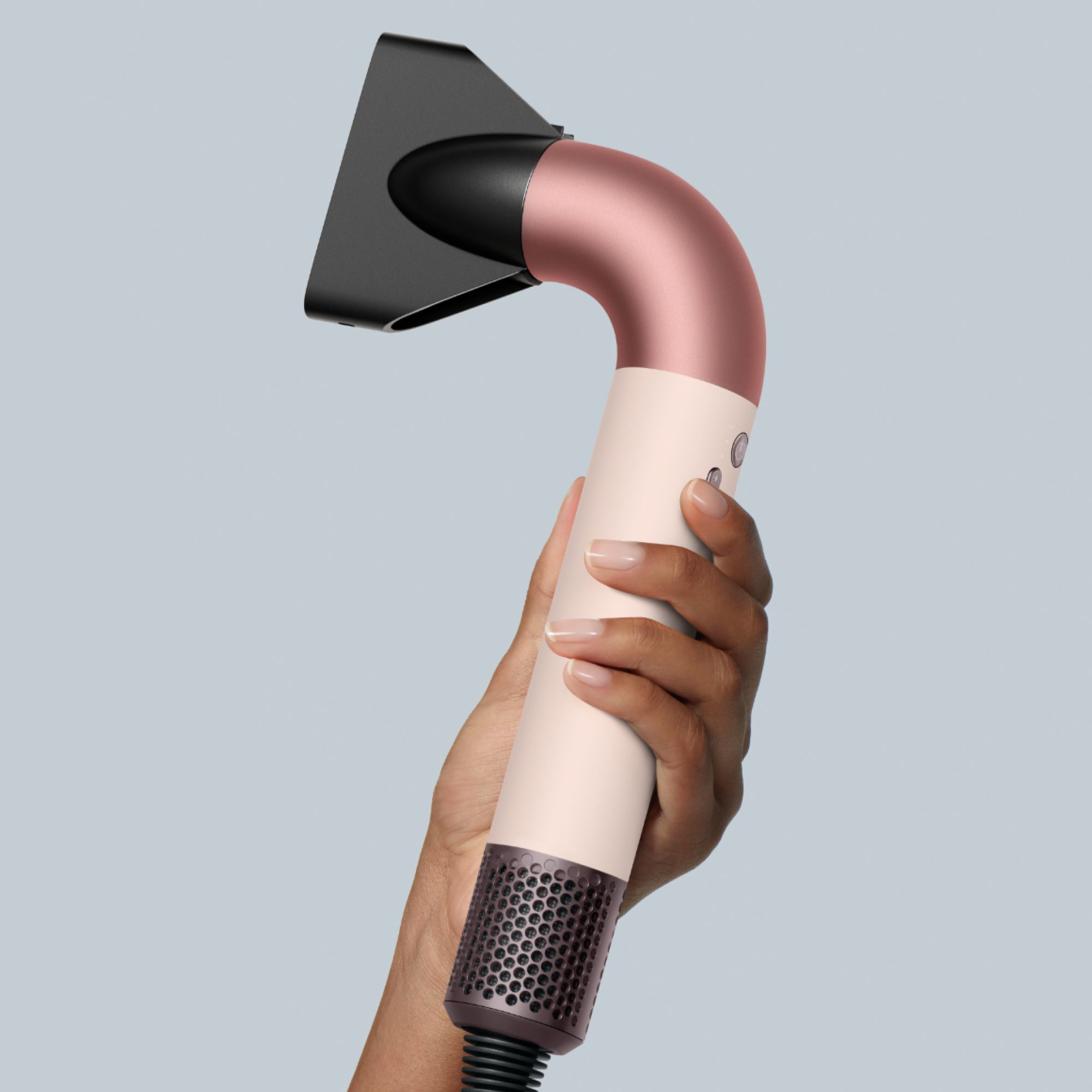 Eine Hand, die einen weißen und roségoldfarbenen Haartrockner hält.