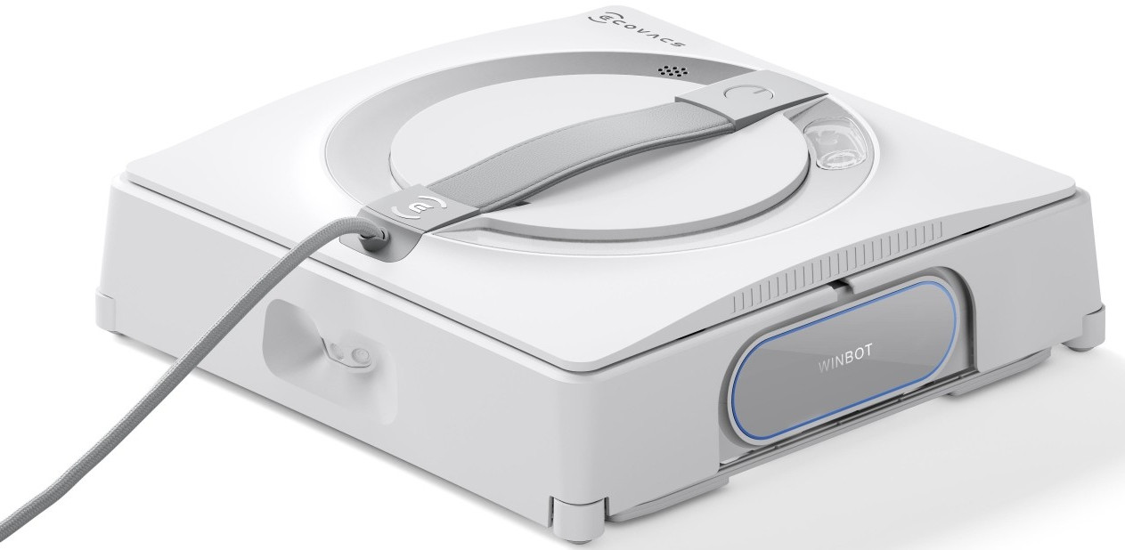 Biały odkurzacz robot z szarymi akcentami. Posiada uchwyt i port ładowania.