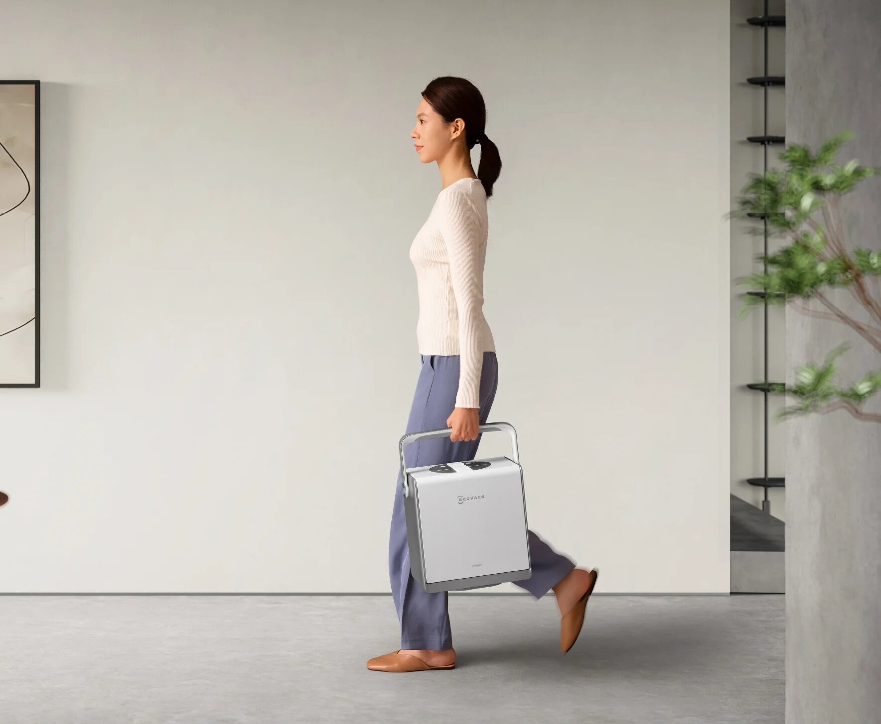 Kobieta idzie, niosąc przenośny oczyszczacz powietrza.