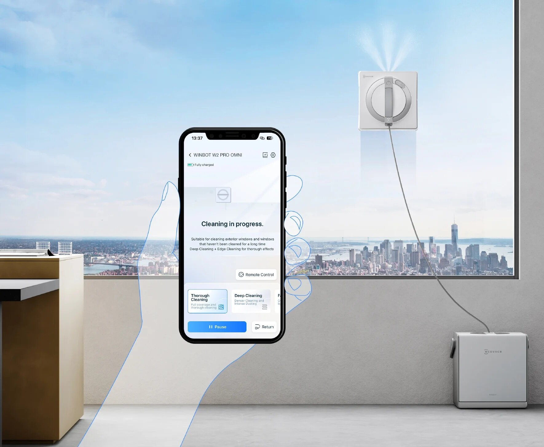 Dłoń trzymająca telefon z aplikacją do czyszczenia, z myjką do okien na oknie.