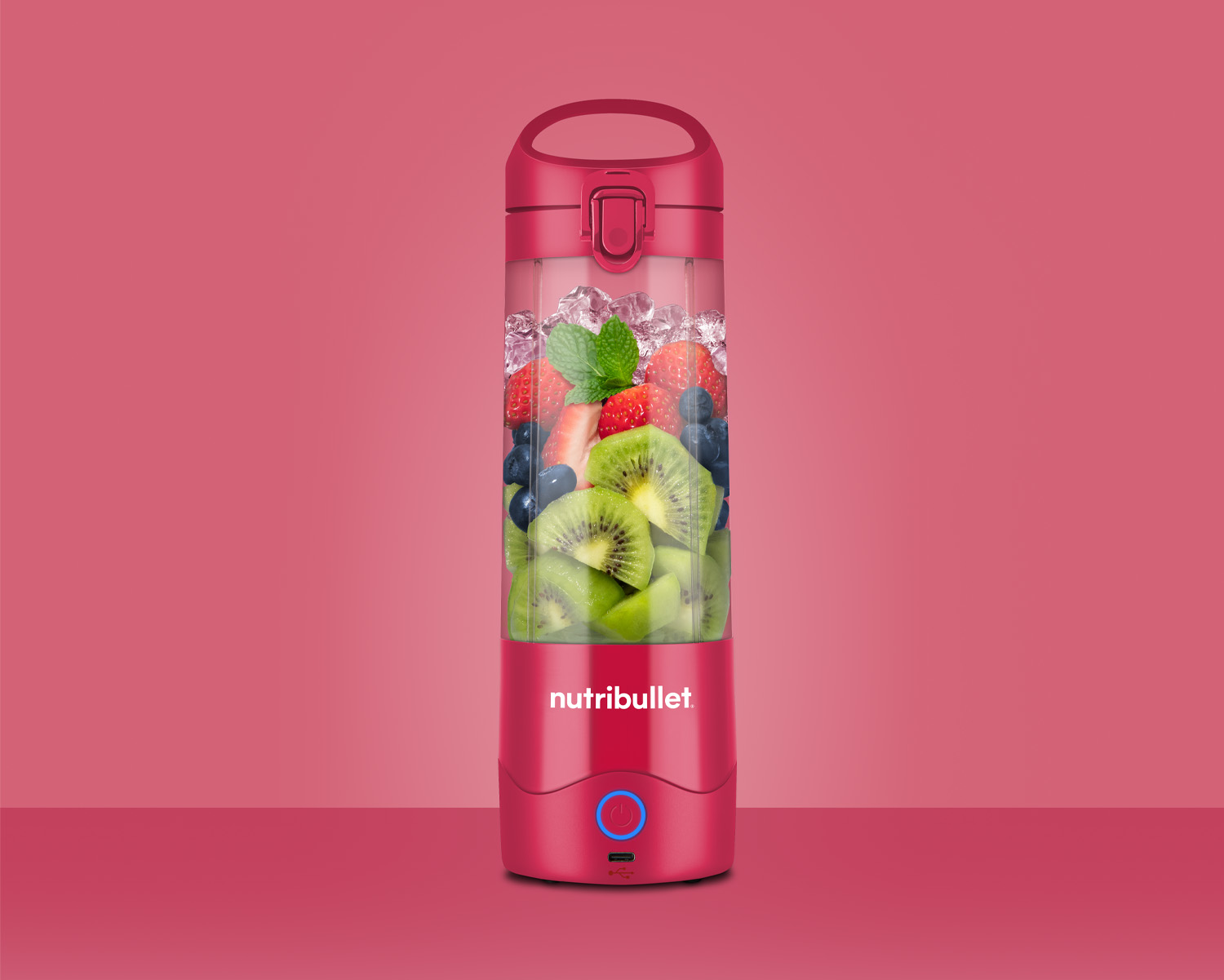 Roter tragbarer Mixer mit Früchten und Eis.