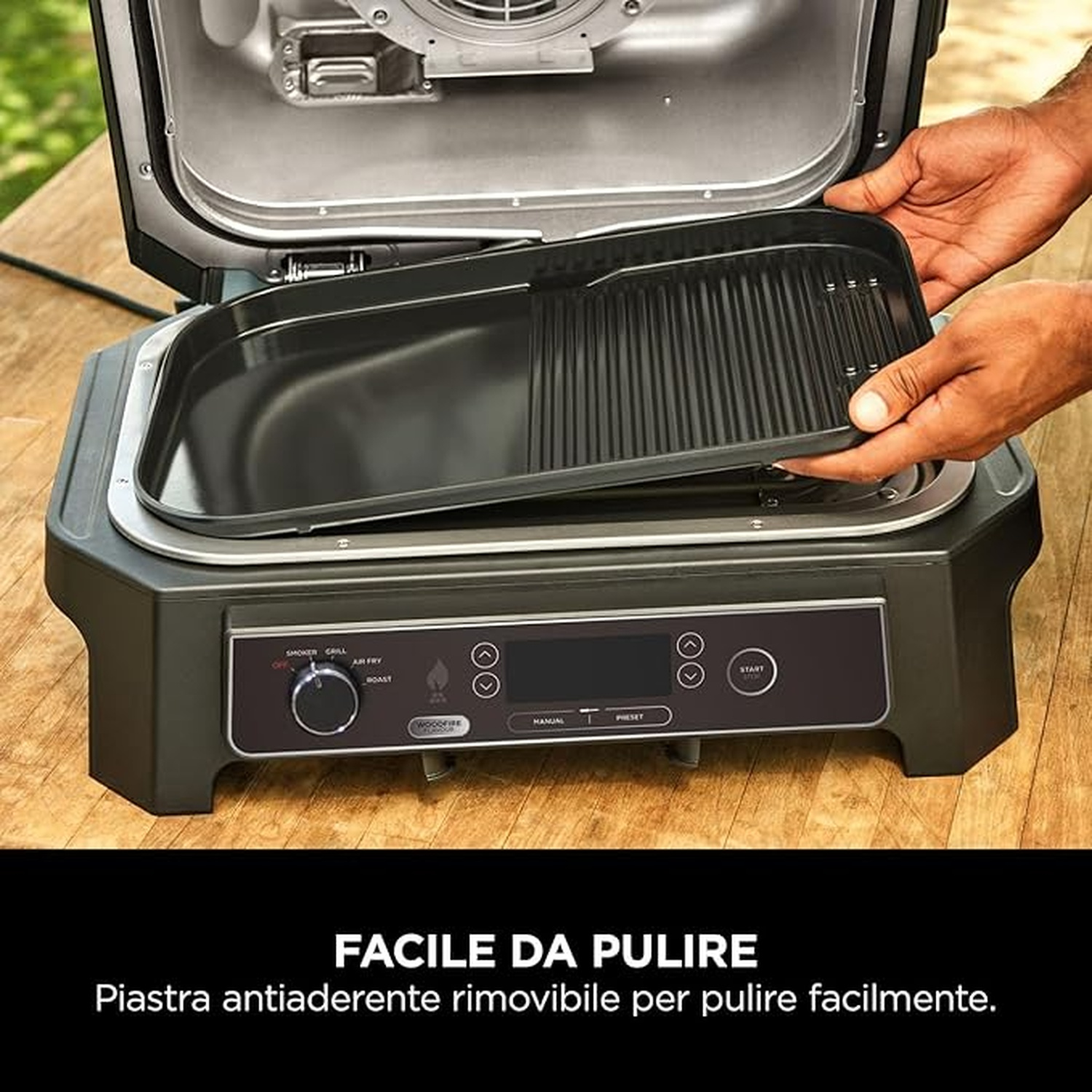 Mani che rimuovono una piastra grill da una griglia da interno nera con display e pulsanti.
