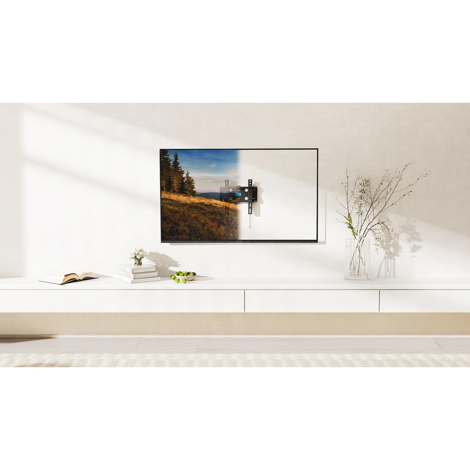 TV montato a parete. Un mobile bianco, fiori e un libro sono posizionati sotto.
