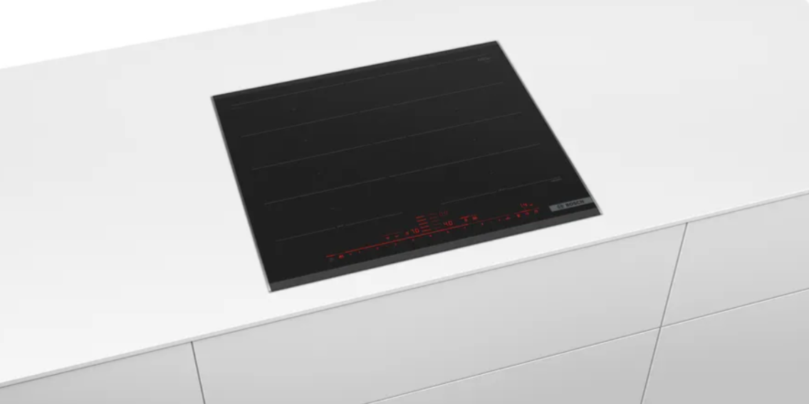 Una placa de inducción negra integrada en una encimera blanca. Pantalla roja. Electrodoméstico de cocina moderno.