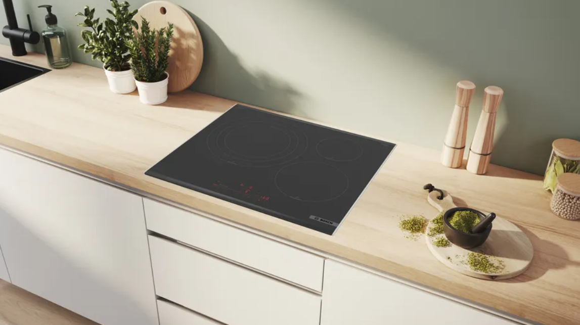 Una placa de inducción sobre una encimera de madera en una cocina moderna.