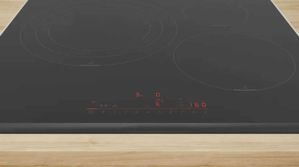 Placa negra con cuatro quemadores. Pantalla roja muestra ajustes. Superficie de madera.