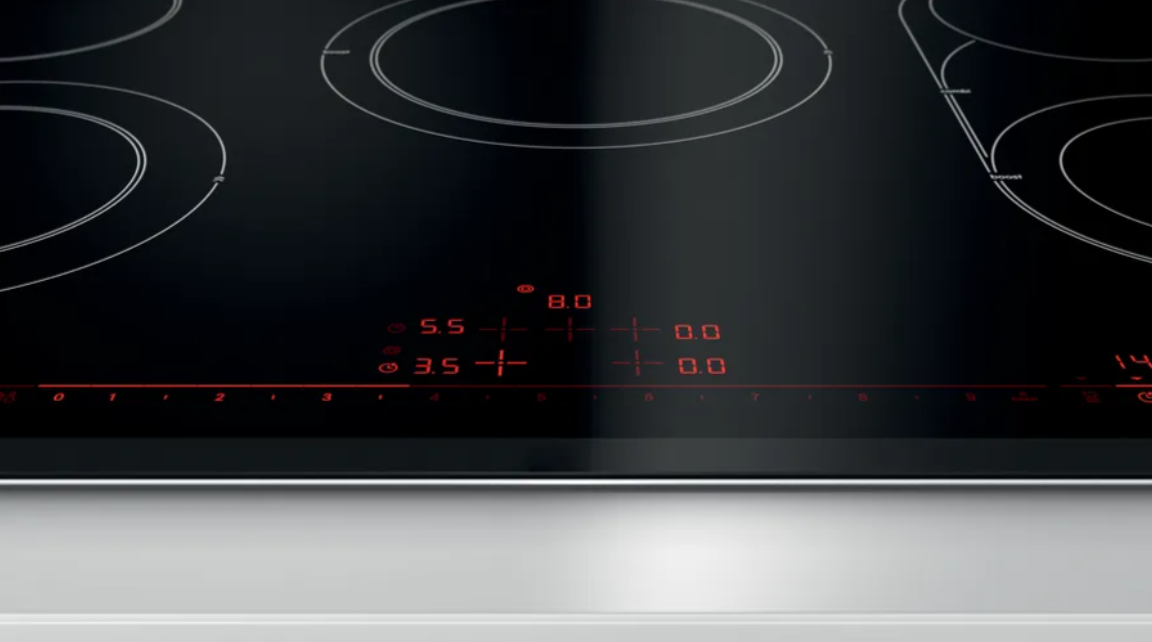 Primer plano de una placa de inducción negra con indicadores de nivel de potencia iluminados en rojo.