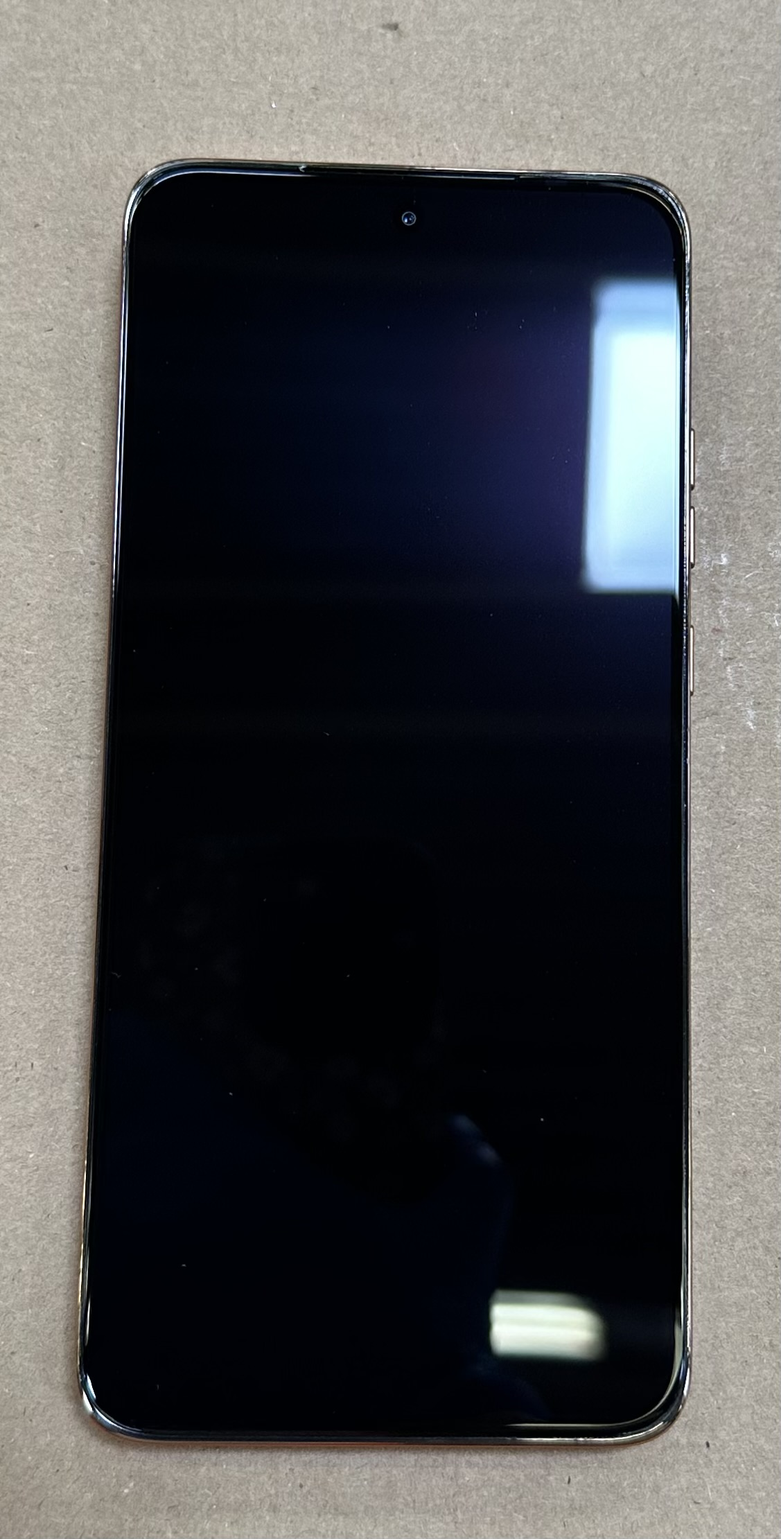 Czarny smartfon na szarej powierzchni. Ekran jest czarny, nie wyświetla żadnej zawartości.