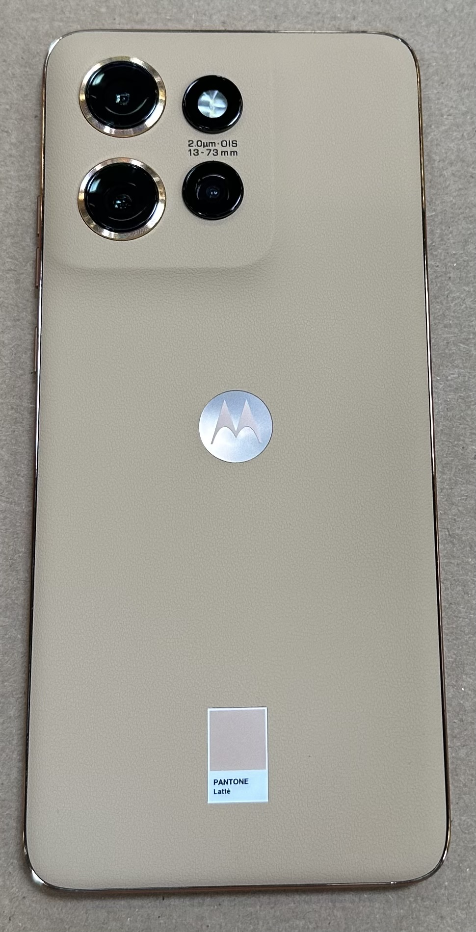 Tył beżowego smartfona z zestawem aparatów i logo Motorola.