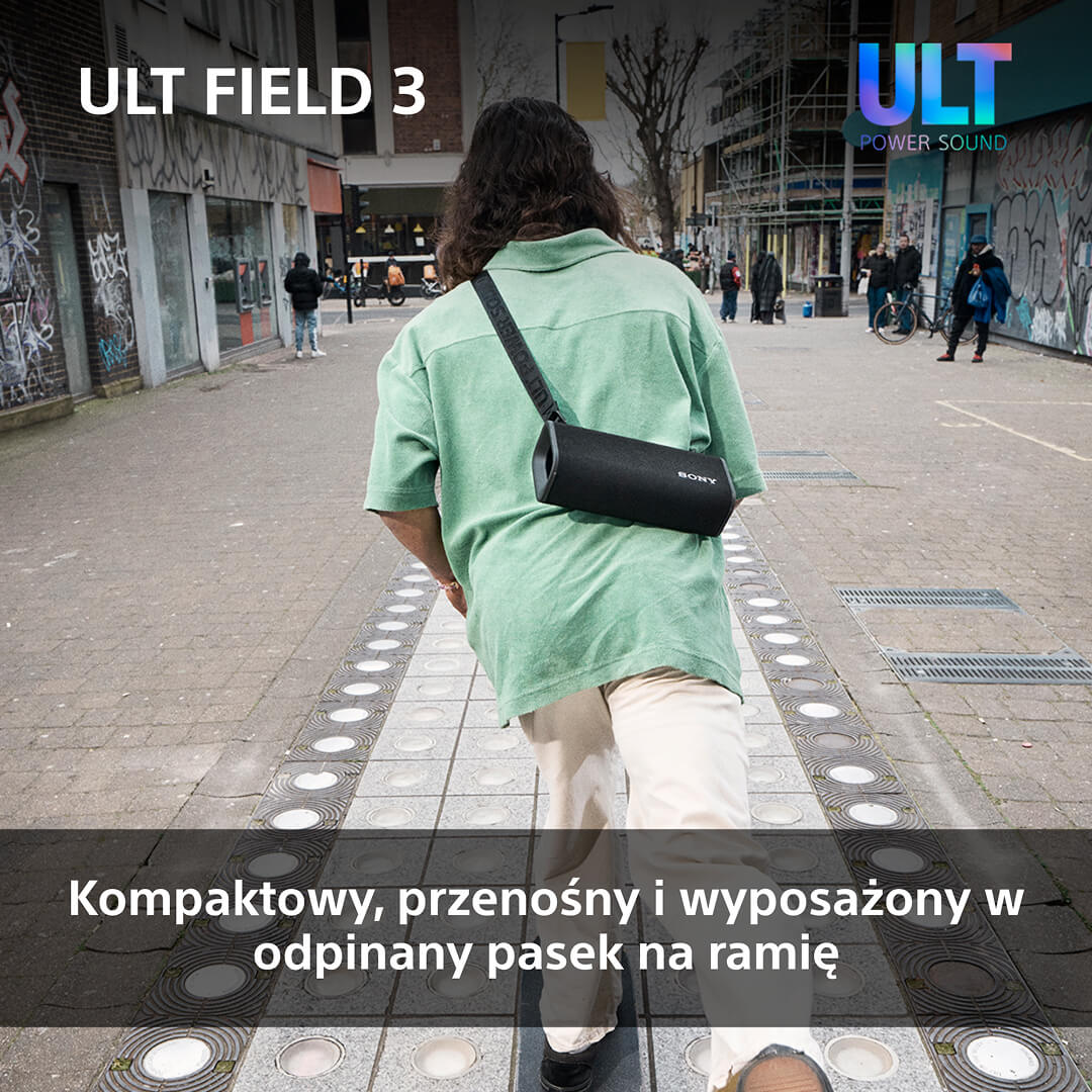 Osoba idąca po wzorzystej ścieżce, niosąca czarny głośnik na ramieniu. Widoczne 'ULT FIELD 3' i 'ULT POWER SOUND'.