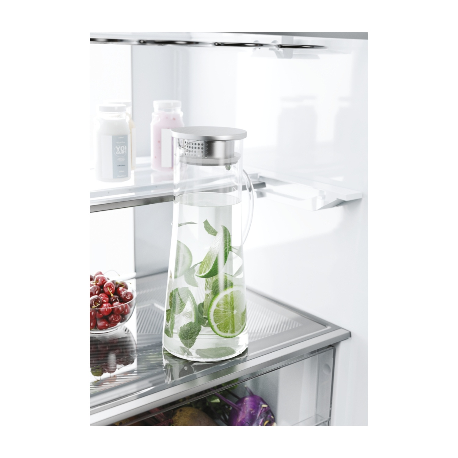 Una caraffa di vetro con acqua, menta e fette di lime all'interno di un frigorifero.