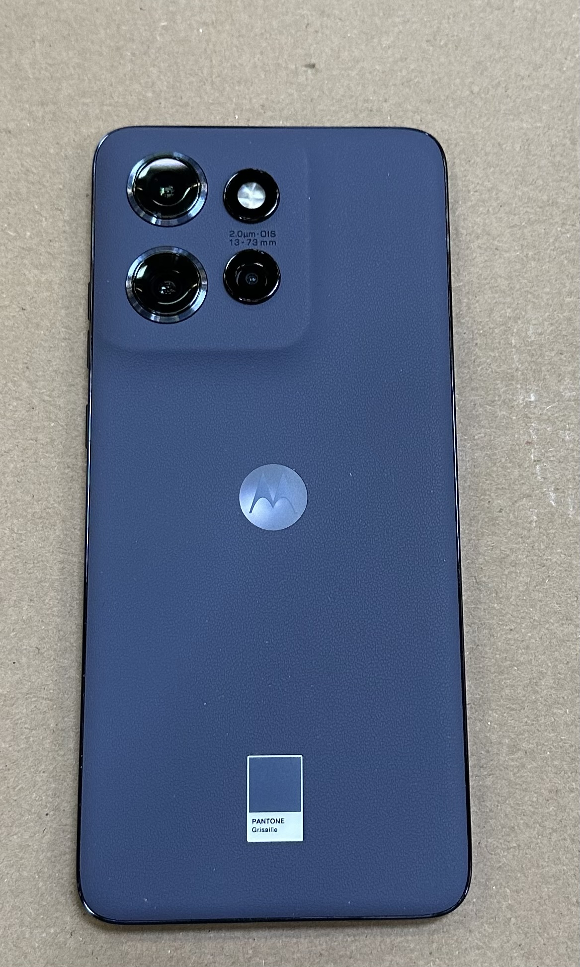 Niebieski telefon Motorola, pokazujący tył z obiektywami aparatu i etykietą Pantone.