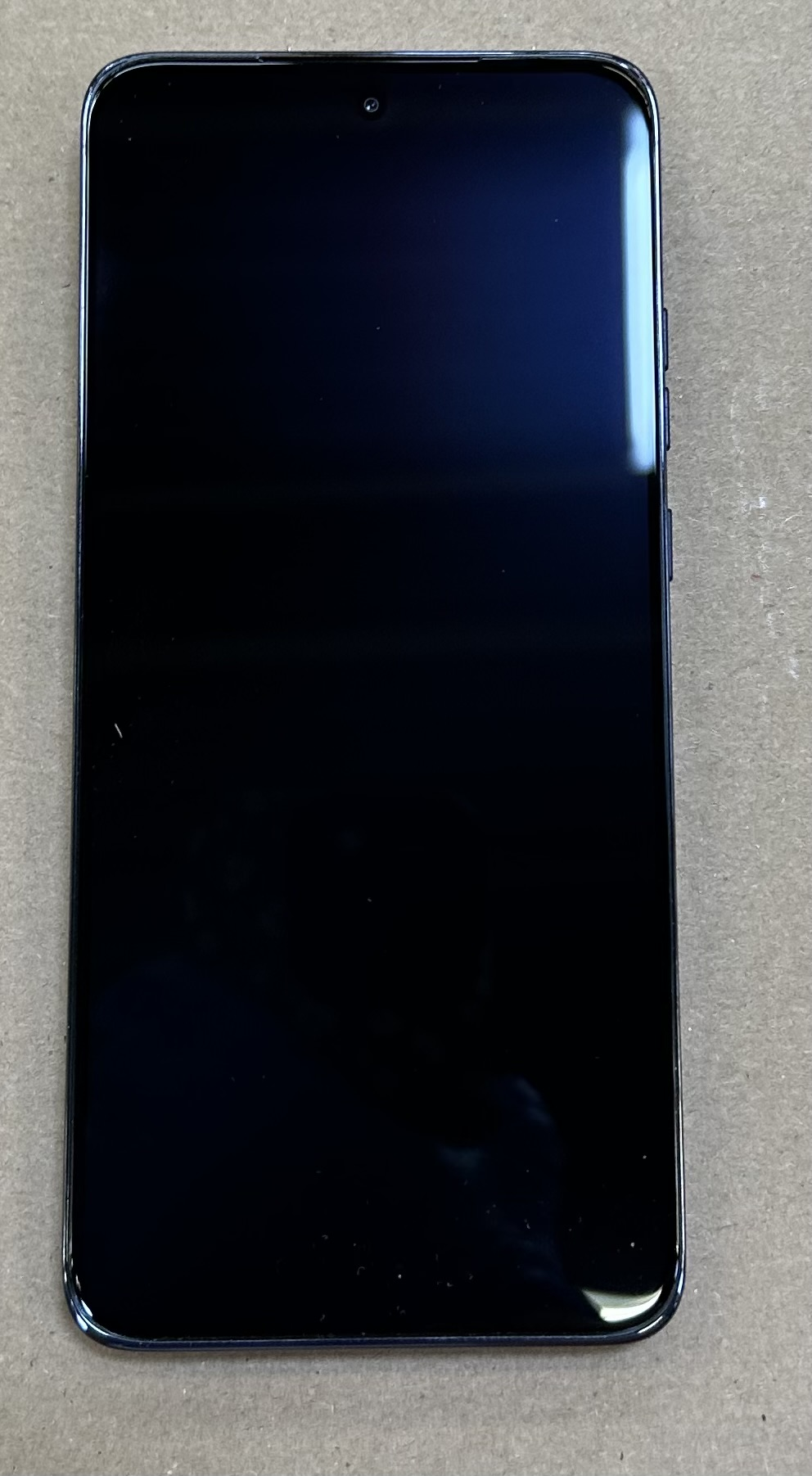 Czarny smartfon z ciemnym ekranem. Telefon ma elegancki, nowoczesny design.