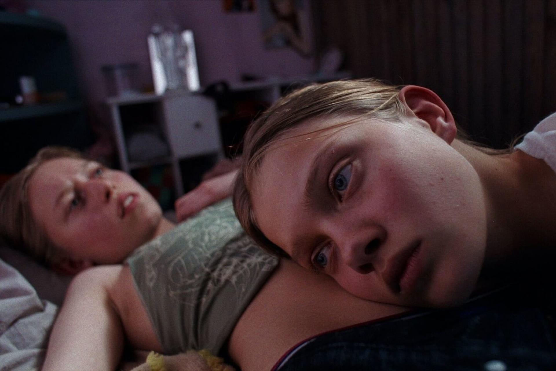Zwei junge Frauen liegen auf einem Bett, eine legt ihren Kopf auf die Brust der anderen.