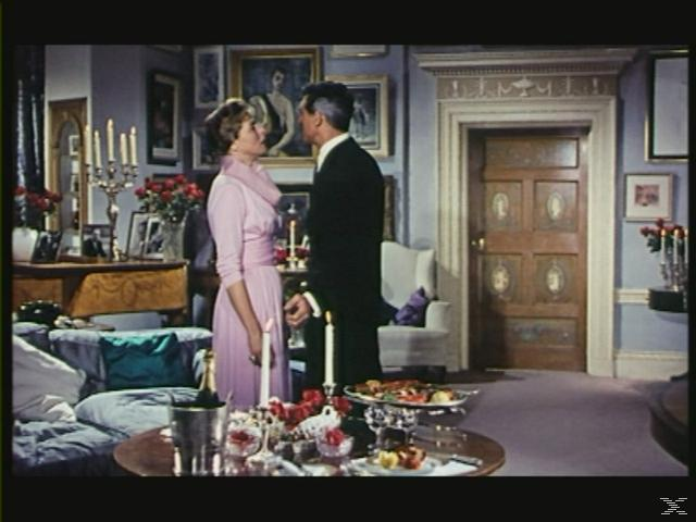Szene aus einem Film: Ein Mann und eine Frau in einem dekorierten Raum mit Kerzen und Essen.
