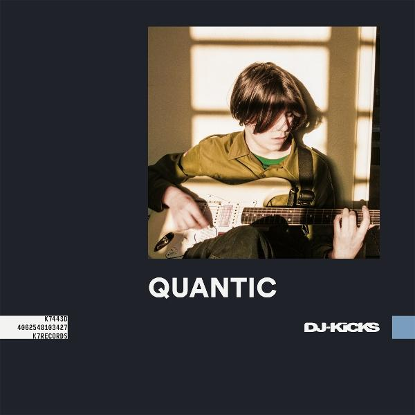 Quantic Albumcover mit einer Person, die Gitarre spielt. Text und blauer Streifen rechts.