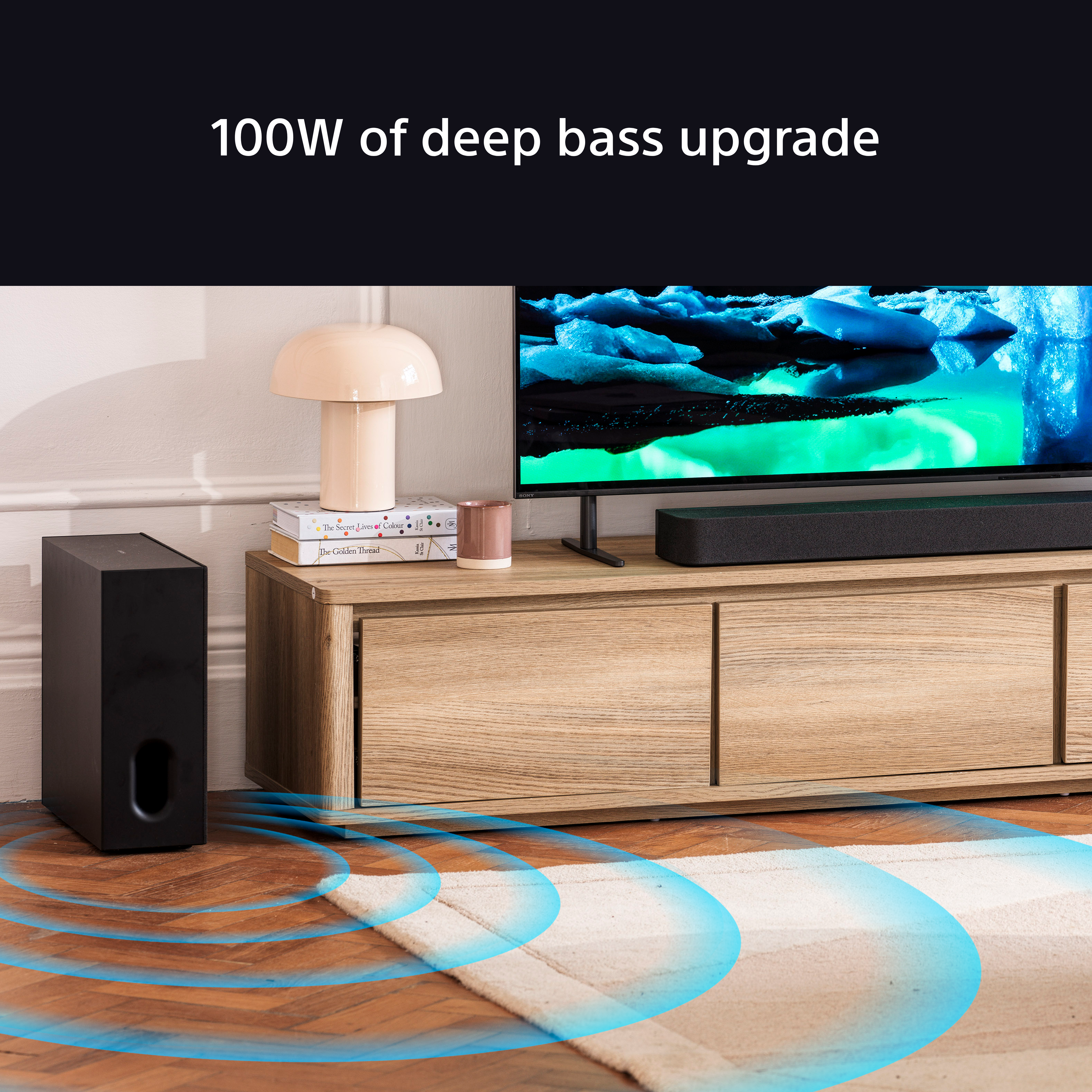 Heimkino-Setup mit Subwoofer, Soundbar, Fernseher und Deko. Blaue Schallwellen gehen vom Subwoofer aus.