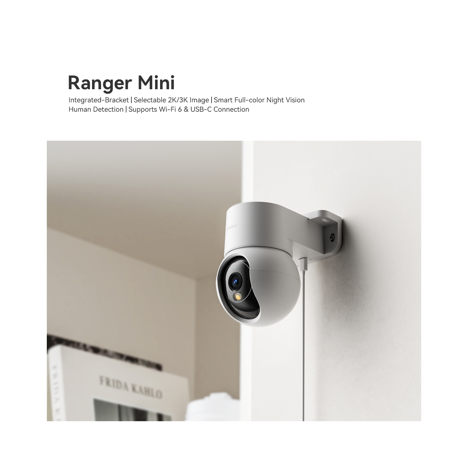 White security camera mounted on a wall. Includes text and a book in the background.