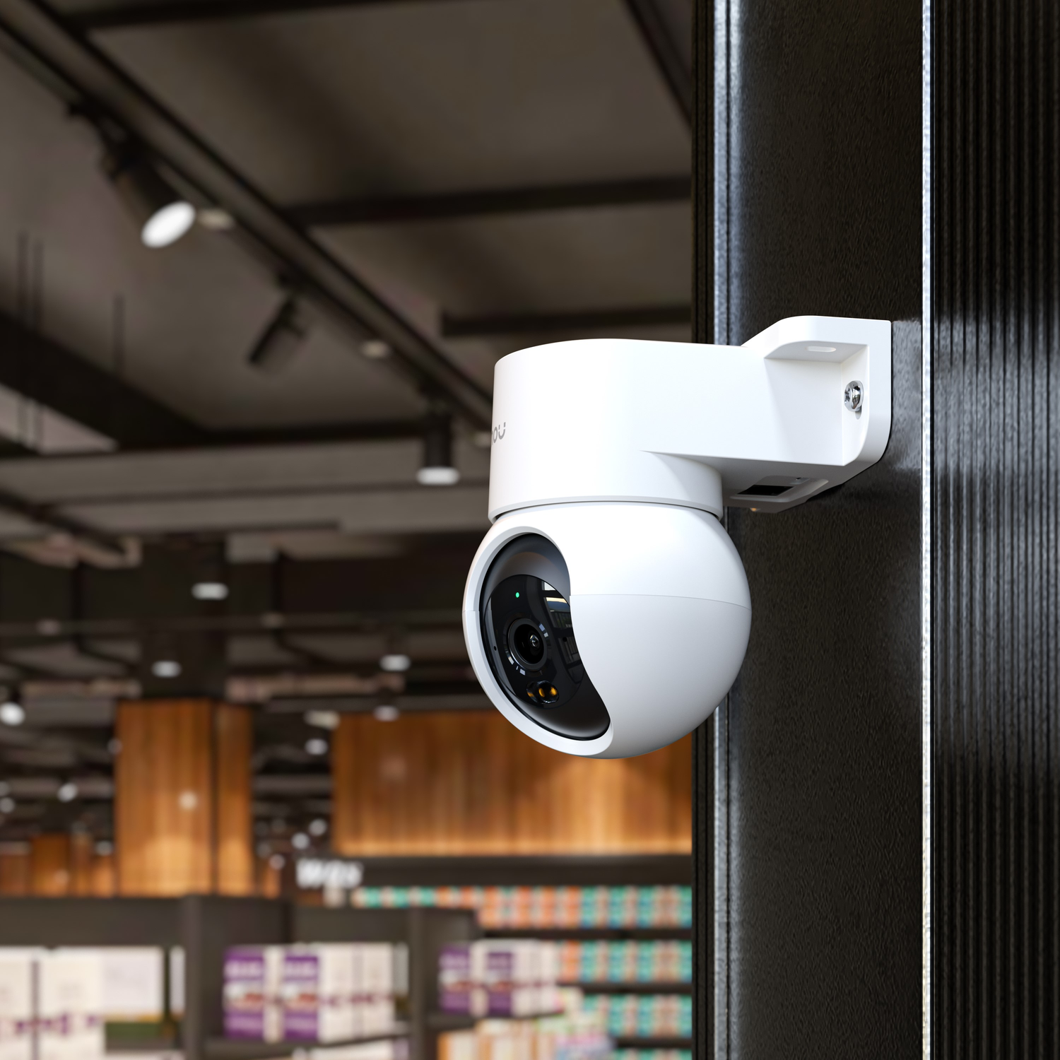 White security camera mounted on a black wall, in a well-lit commercial setting.