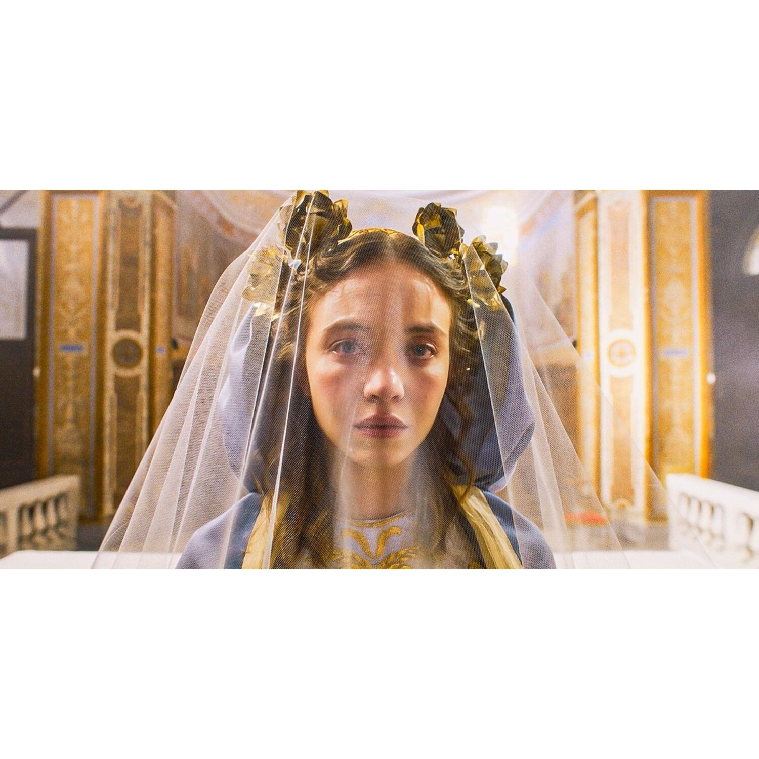 Femme avec un voile blanc, dans un cadre d'église, regardant la caméra.