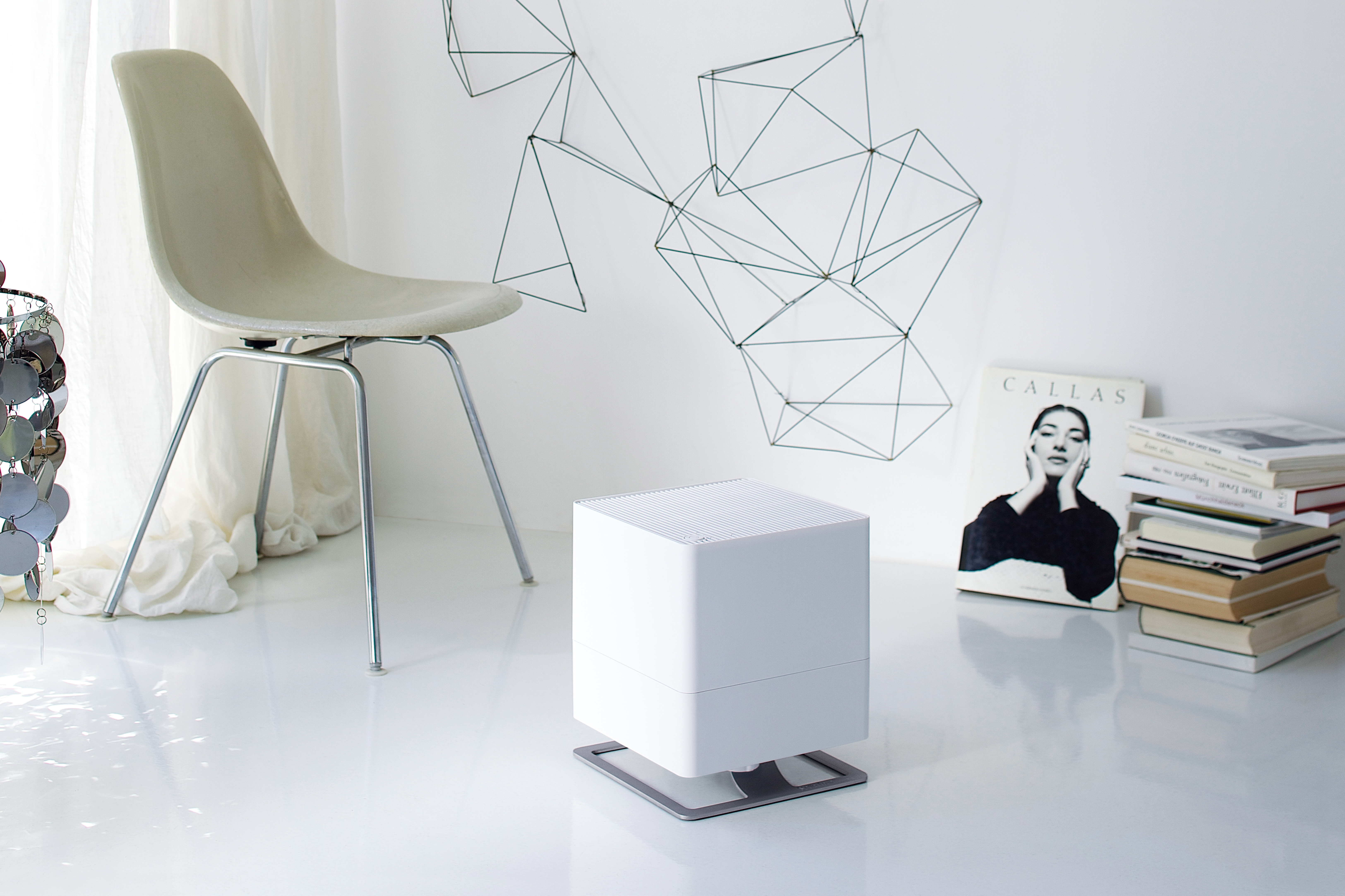 Stanza minimalista bianca con purificatore d'aria bianco e sedia.
