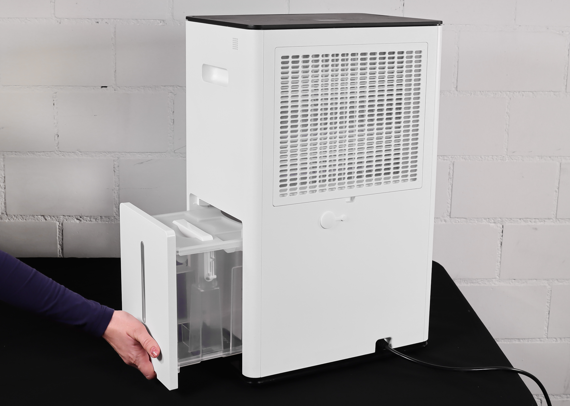 Deumidificatore bianco con serbatoio dell'acqua rimosso. Il deumidificatore è su una superficie nera.